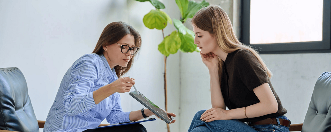 2 women look at tablet one presenting