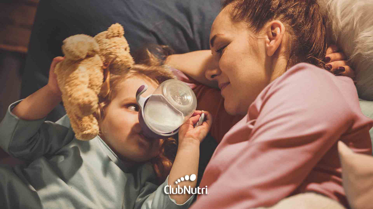Niño tomando vasito de leche con su mamá