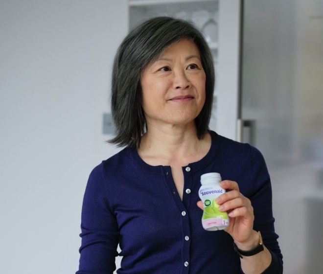 Woman in a kitchen holding an open bottle of Souvenaid 