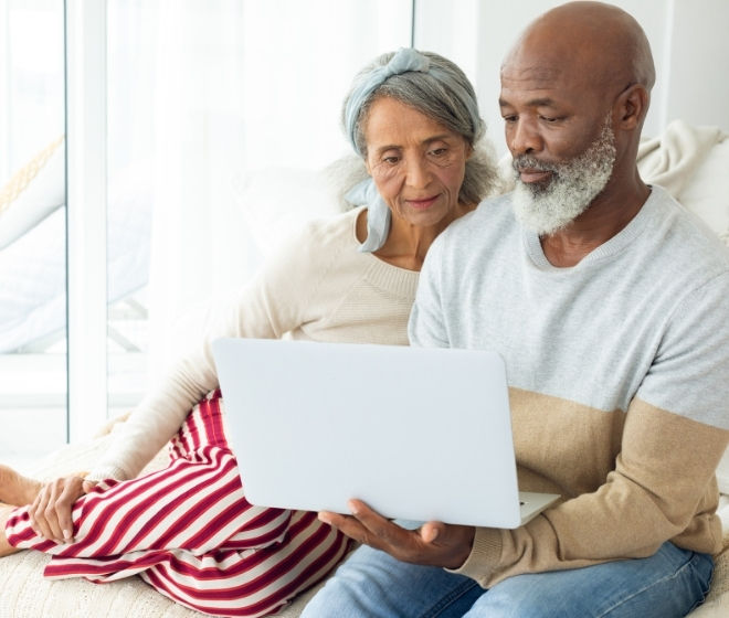 Man and woman sitting on couch using their laptop