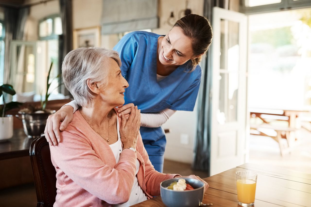 Shot of a young nurse checking up on a senior woman during breakfast at a nursing home