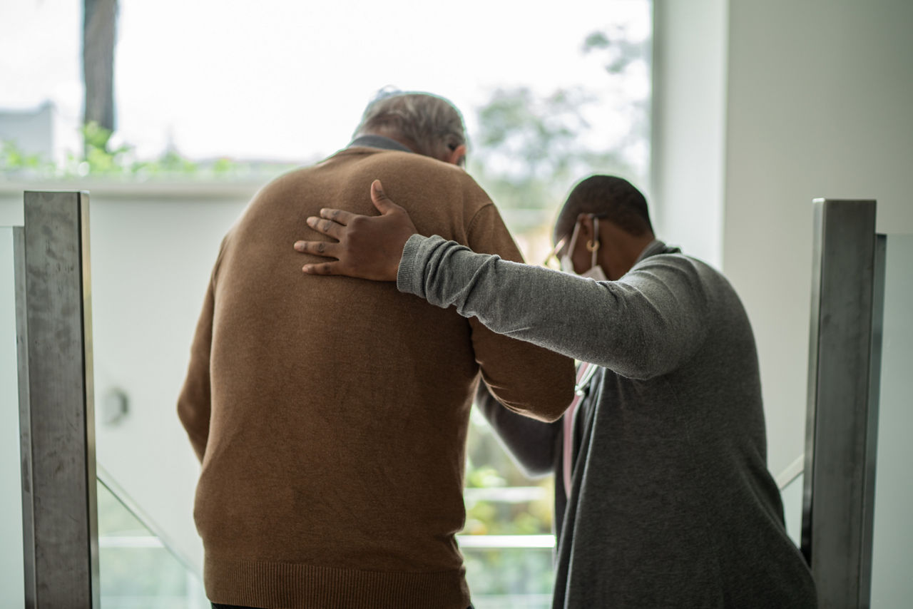 Home caregiver helping patient walking