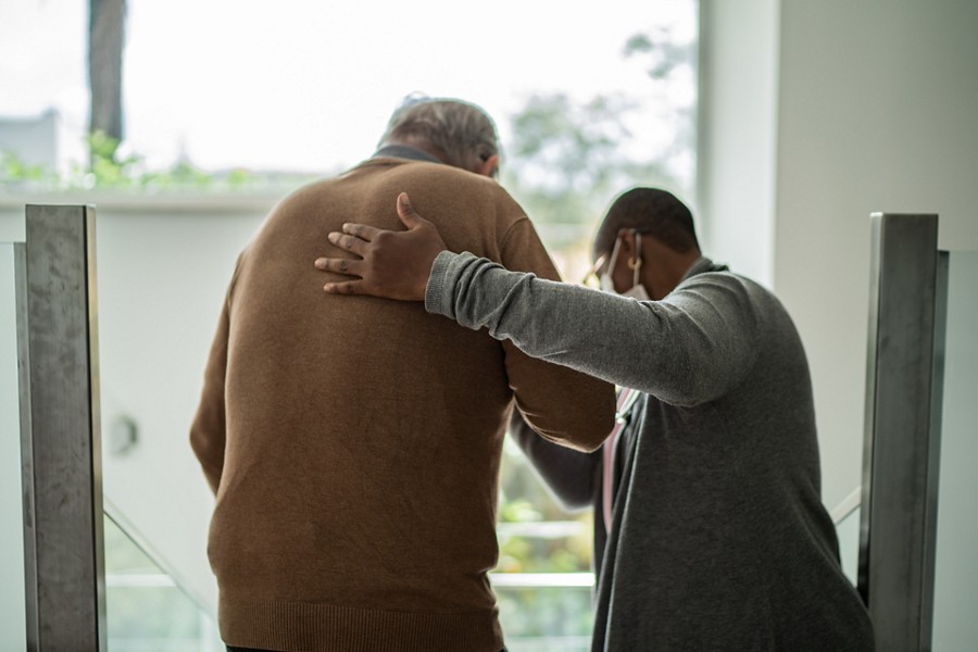 Home caregiver helping patient walking
