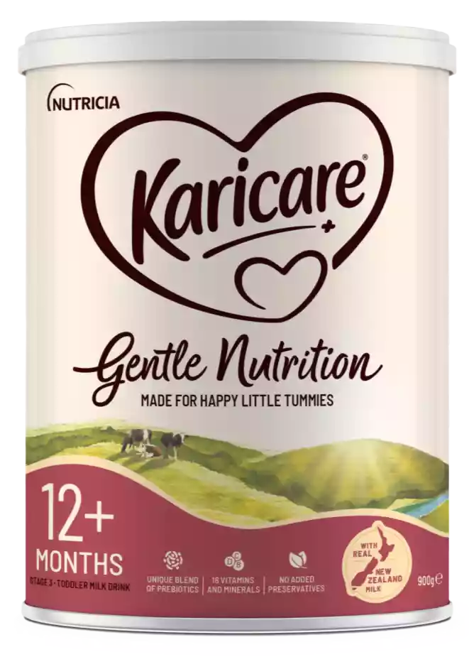 A Karicare Gentle Nutrition toddler milk drink tin is shown against a transparent background. The front of the tin highlights that it is suitable for children aged 12+ months and is made for happy little tummies. Icons emphasize a unique blend of prebiotics, 16 vitamins and minerals, and no added preservatives. The design features a pastoral New Zealand landscape with cows and a badge stating it is made with real New Zealand milk, and the net weight is 900 g.