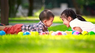 Big sister and her younger brother in park smiling