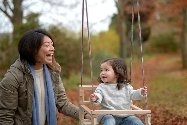 kid on swing with happy mother