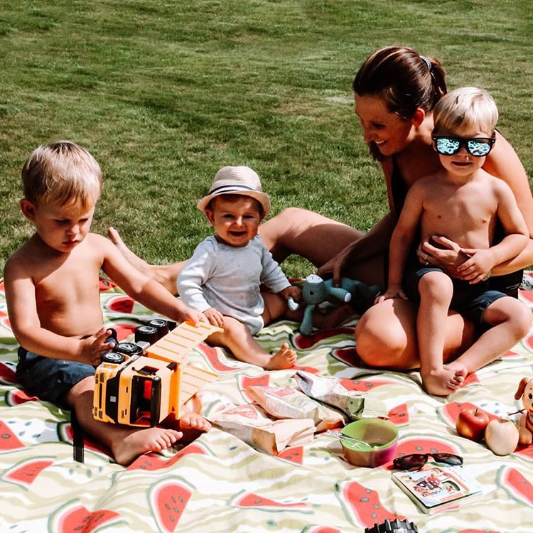 Mutter mit Kleinkindern auf der Picknickdecke im Sommer