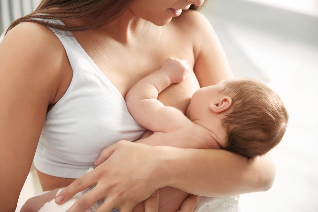 Baby krijgt borstvoeding in een comfortabele voedingshouding, wat de voordelen van borstvoeding en een gezonde ontwikkeling ondersteunt.