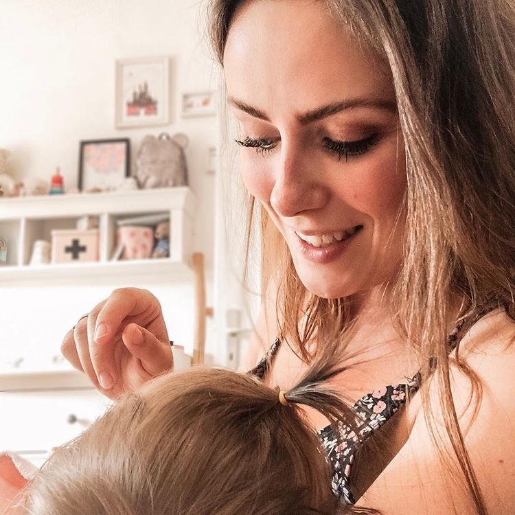 Mutter hält Baby im Arm und schaut herab