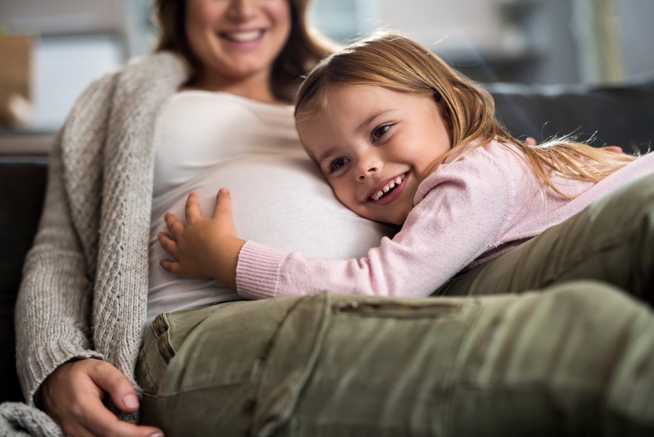 Un petit enfant tient le ventre de sa mère enceinte