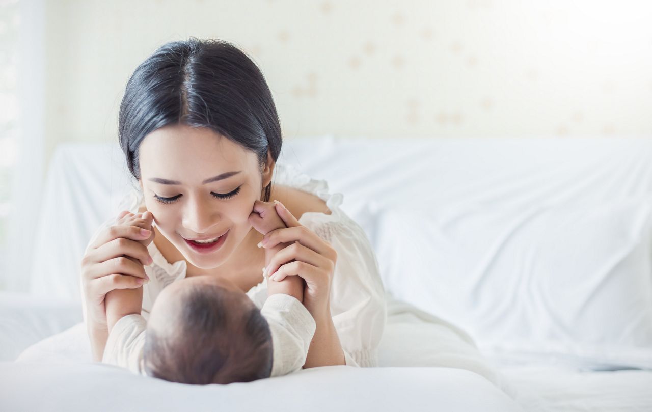 Happy asian mother playing with newborn baby, baby talking to mother. Health care and medical family love lifestyle motherÃ¢??s day nursery concept