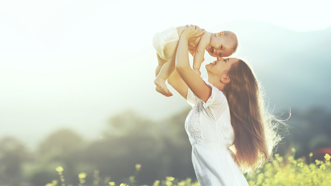 happy harmonious family outdoors. mother throws baby up, laughing and playing in the summer on the nature