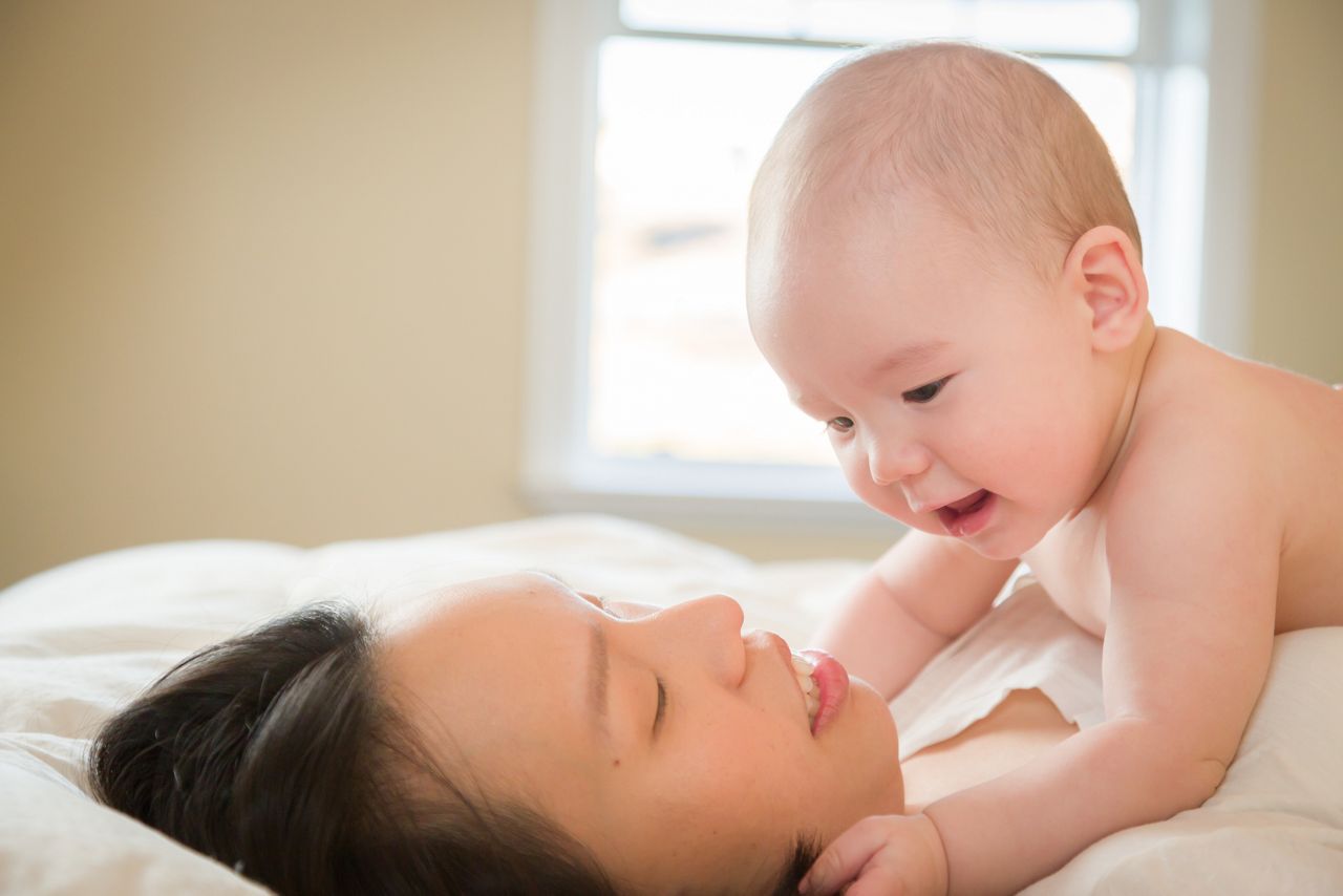 Young Mixed Race Chinese and Caucasian Baby Boy Laying In His Bed with His Mother.