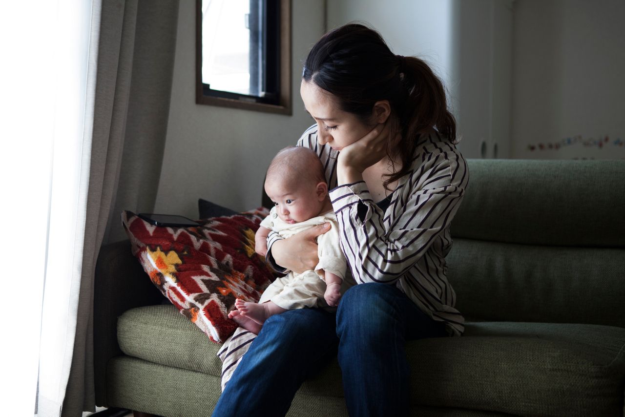 Mae cansada com bebe no colo