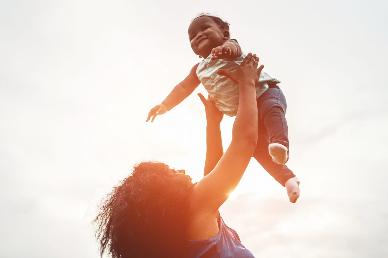 Happy african mother playing with her daughter outdoor - Afro mum and child having fun together - Family, happiness and love concept - Soft focus on woman face