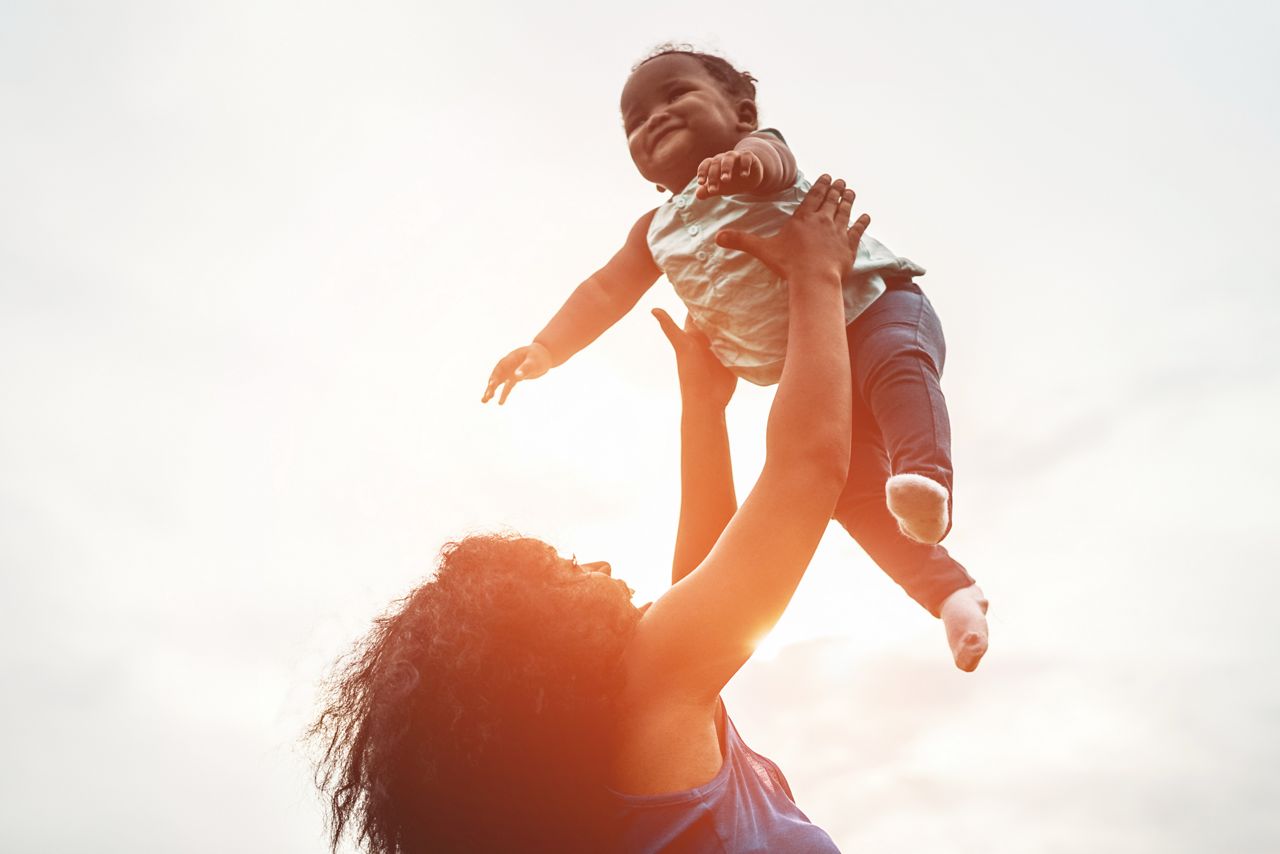 Mae brinca com seu bebe a luz do sol