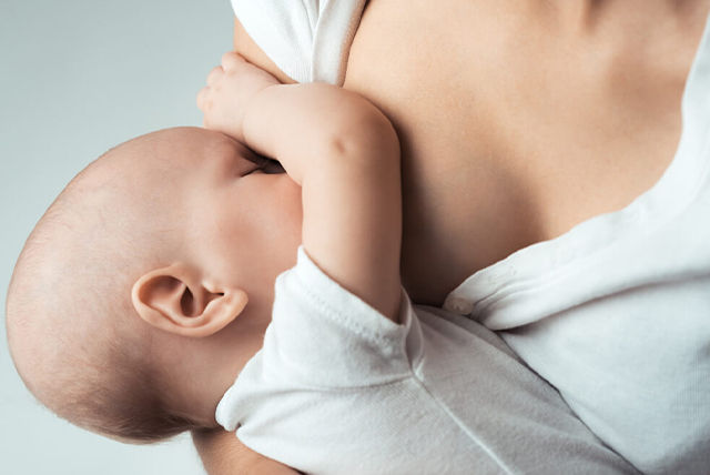 mamá amamantando a su bebé vestidos de blanco