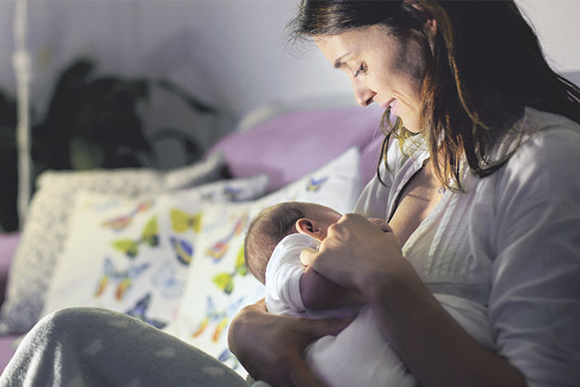 mamá amamantando bebé ambos vestidos de blanco