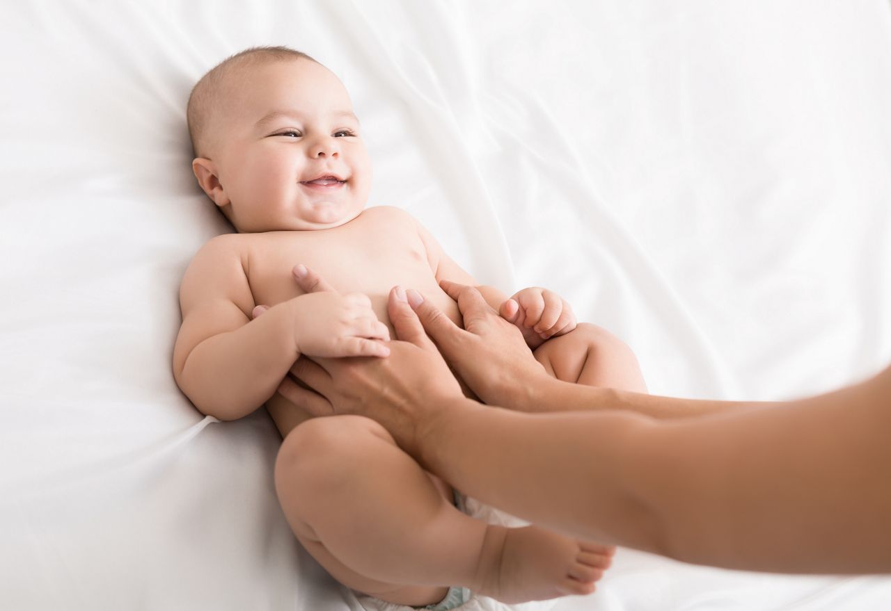 Colics prevention. Masseur massaging tummy of newborn baby, healthcare and babycare, copy space