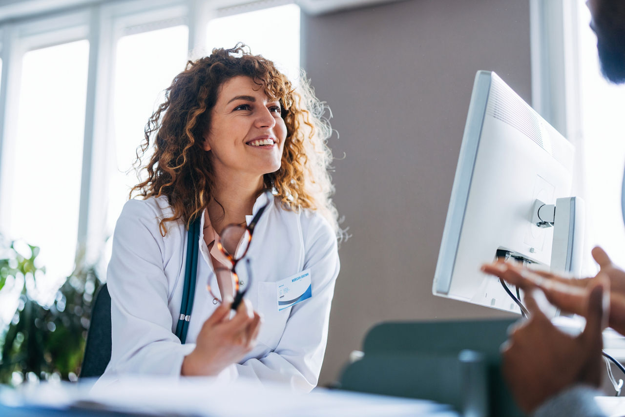 A cheerful and professional female doctor is engaging with a patient during a medical consultation, emphasizing trust and open communication in a bright and welcoming office environment.