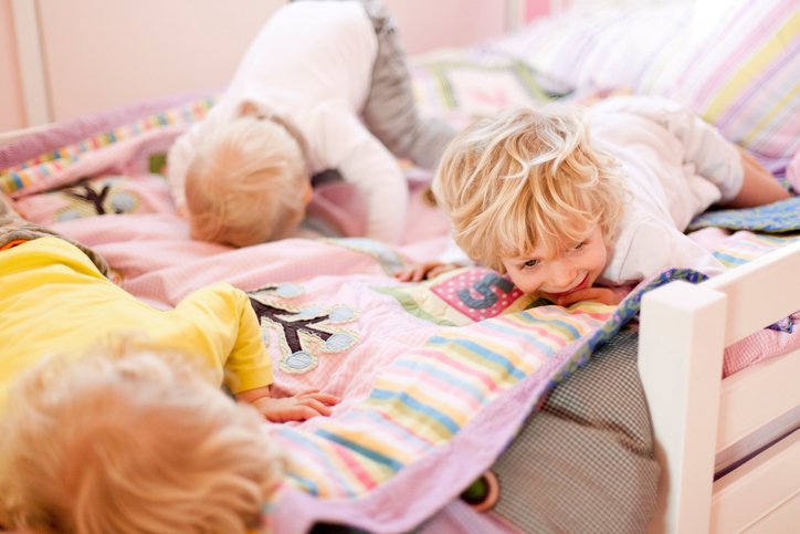 Three young brothers crawling face down on bed