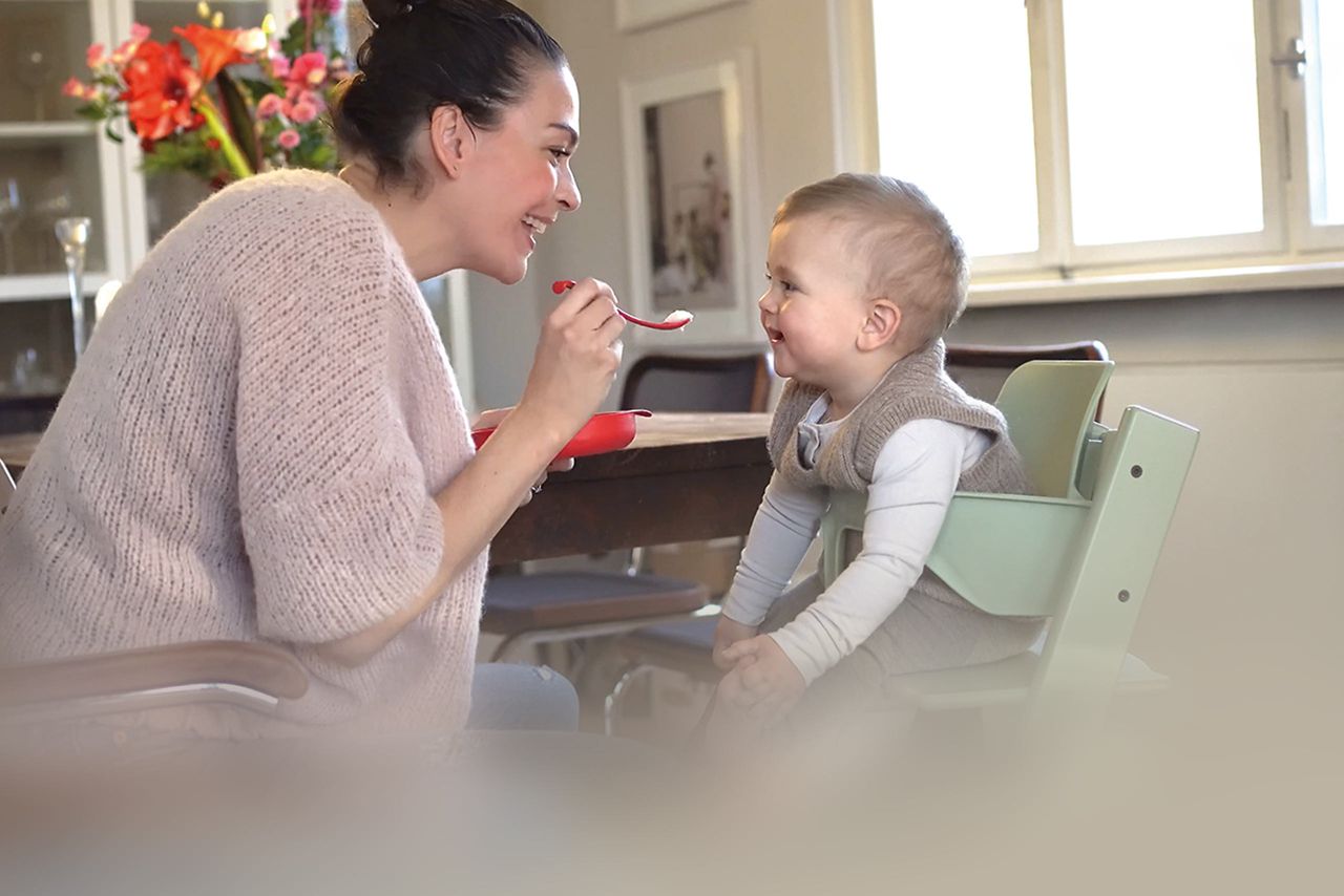 Mama füttert Baby mit Brei 