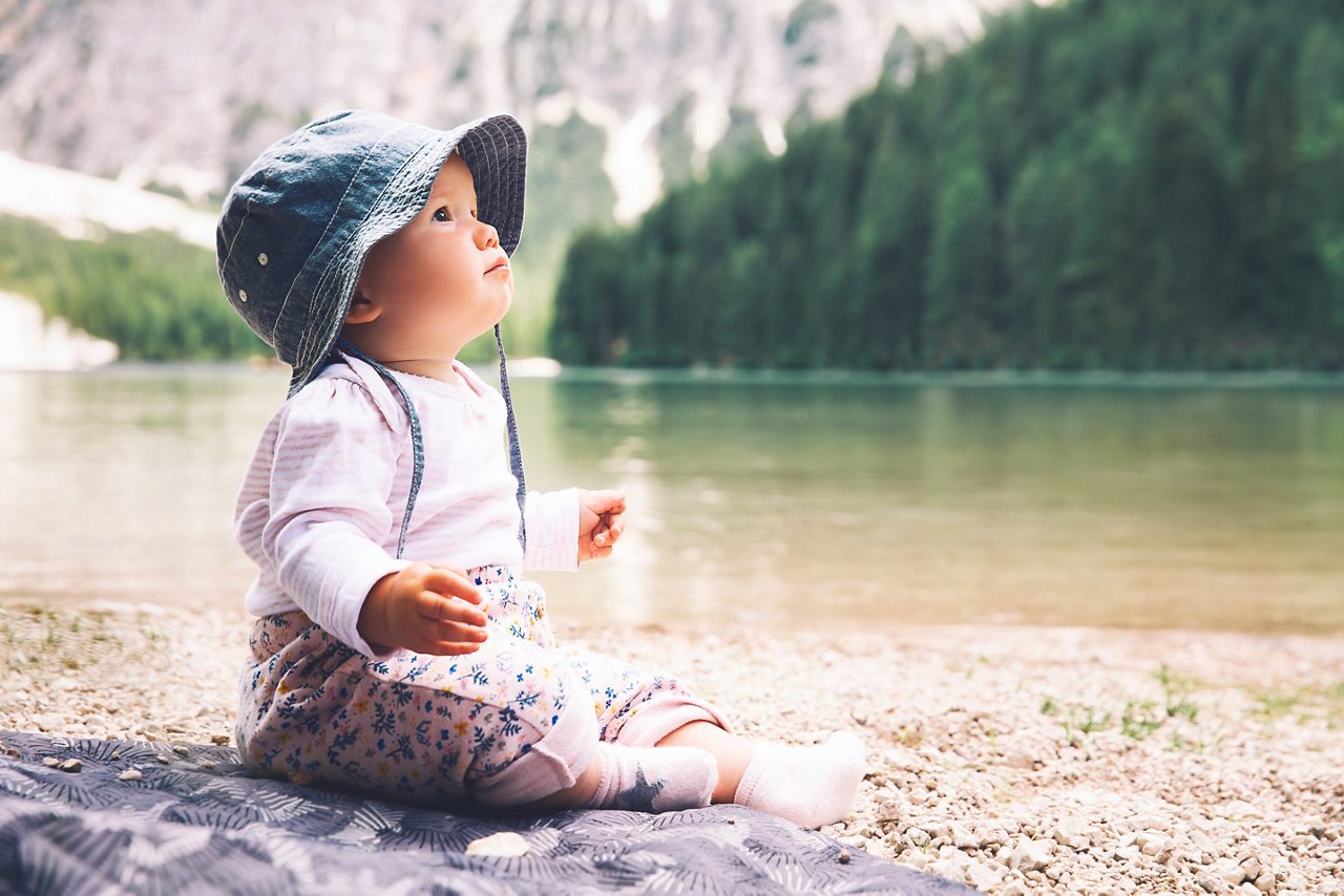 Baby sitzt an einem See in den Bergen
