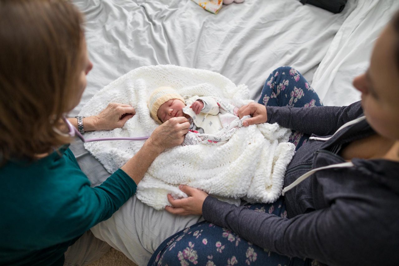 Hebamme untersucht Neugeborenes im Wochenbett