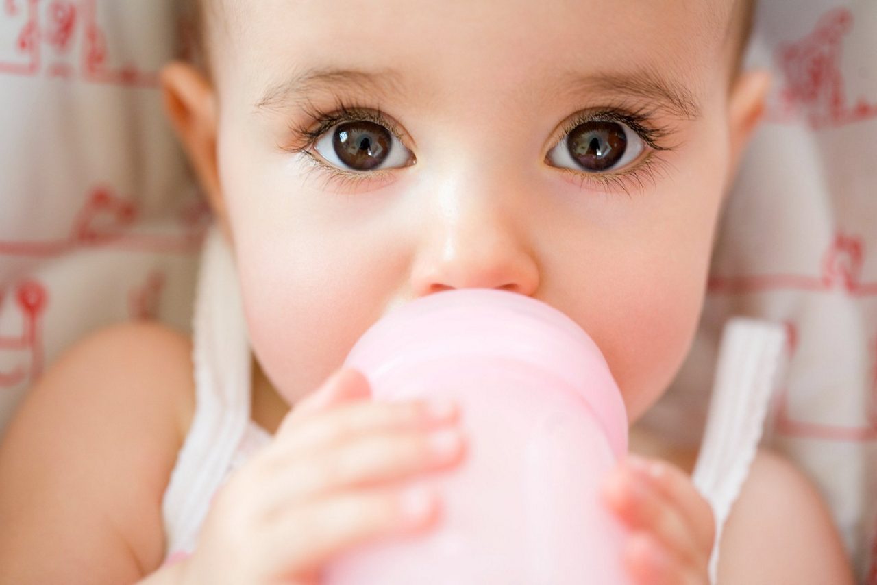 Baby mit braunen Augen trinkt aus dem Fläschchen