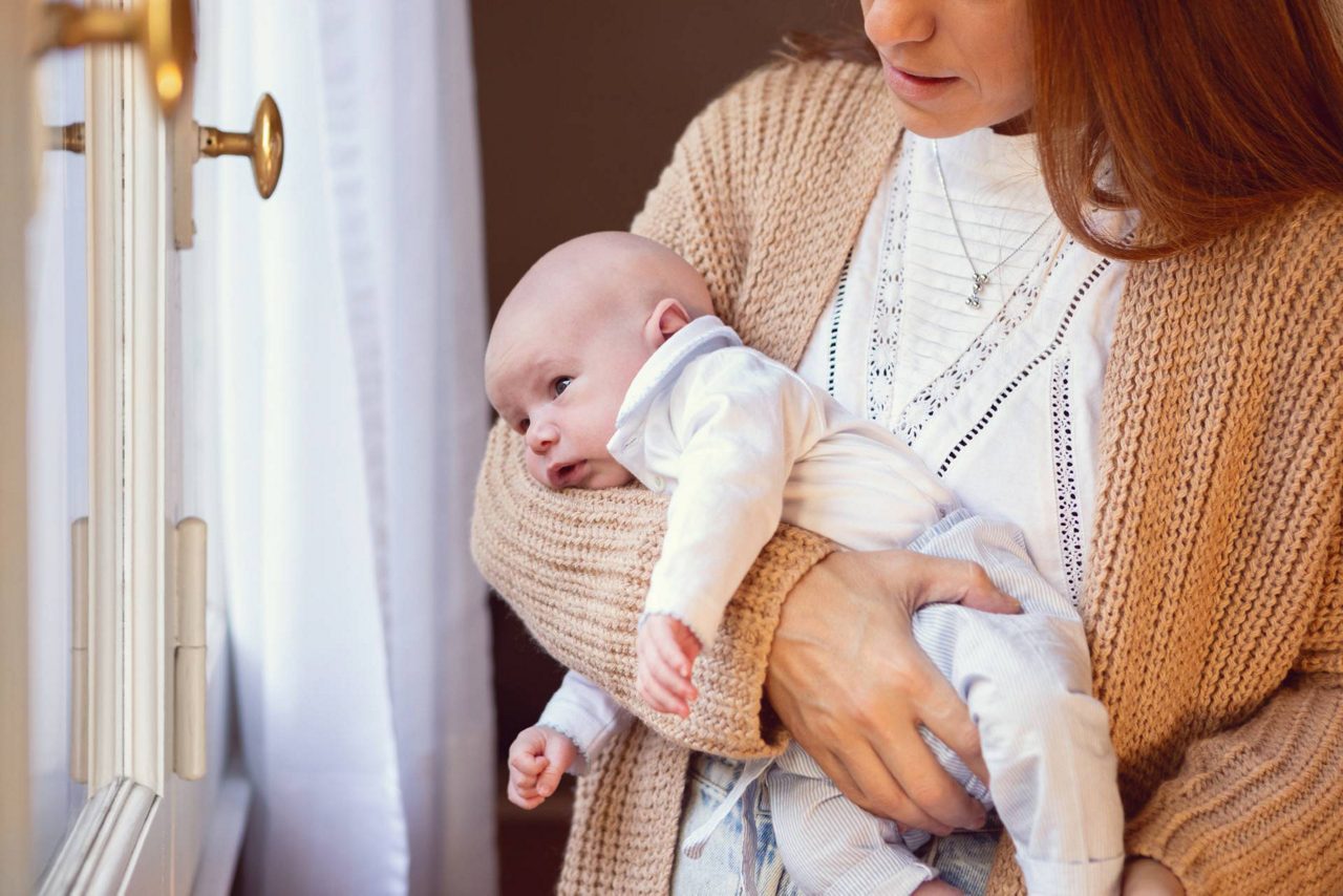 Mutter hält ihr Baby im Fliegergriff
