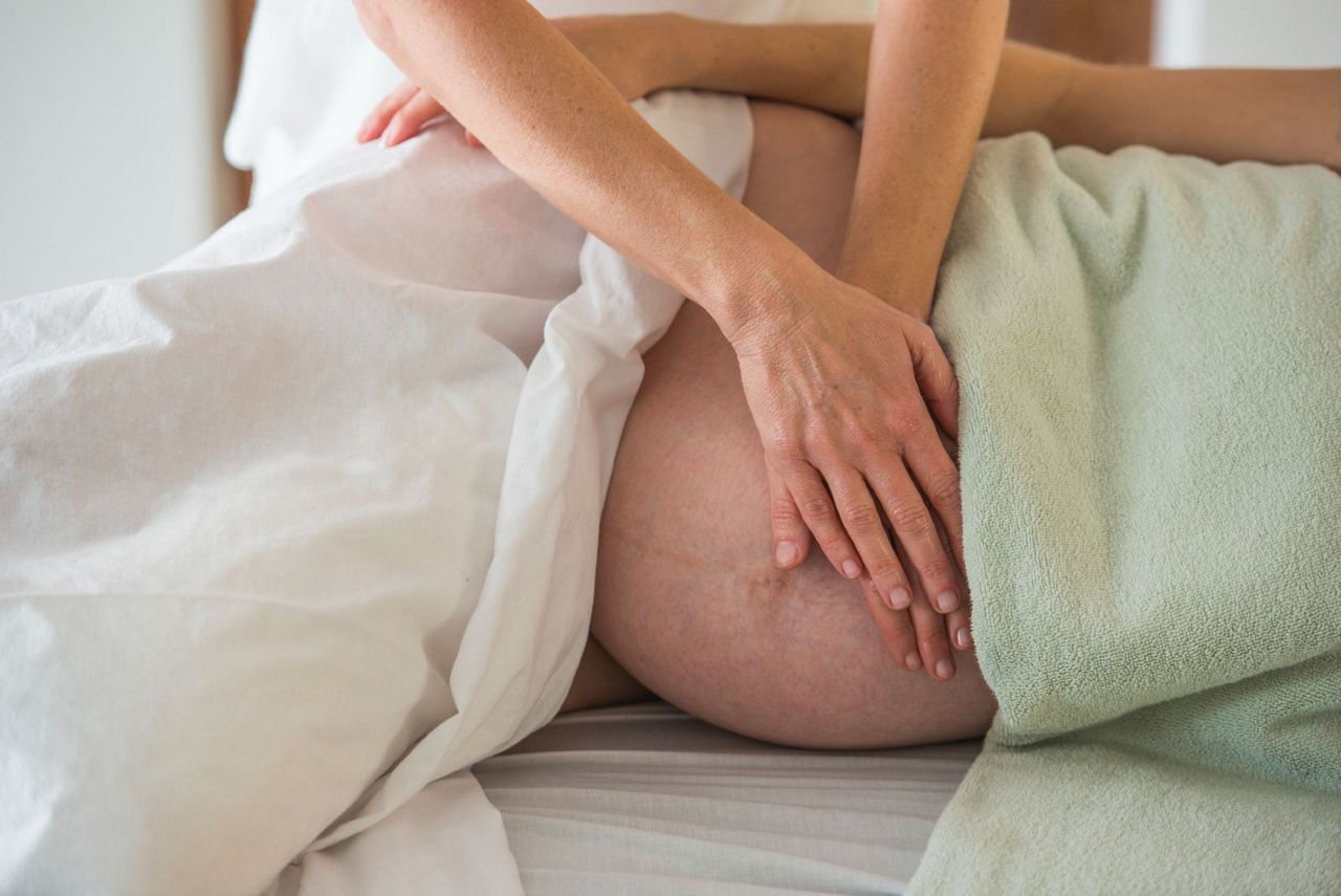 Schwangere Frau hält sich schmerzenden Bauch