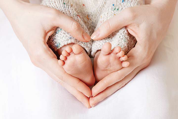 Baby Füße mit Händen drum herum in Herzform