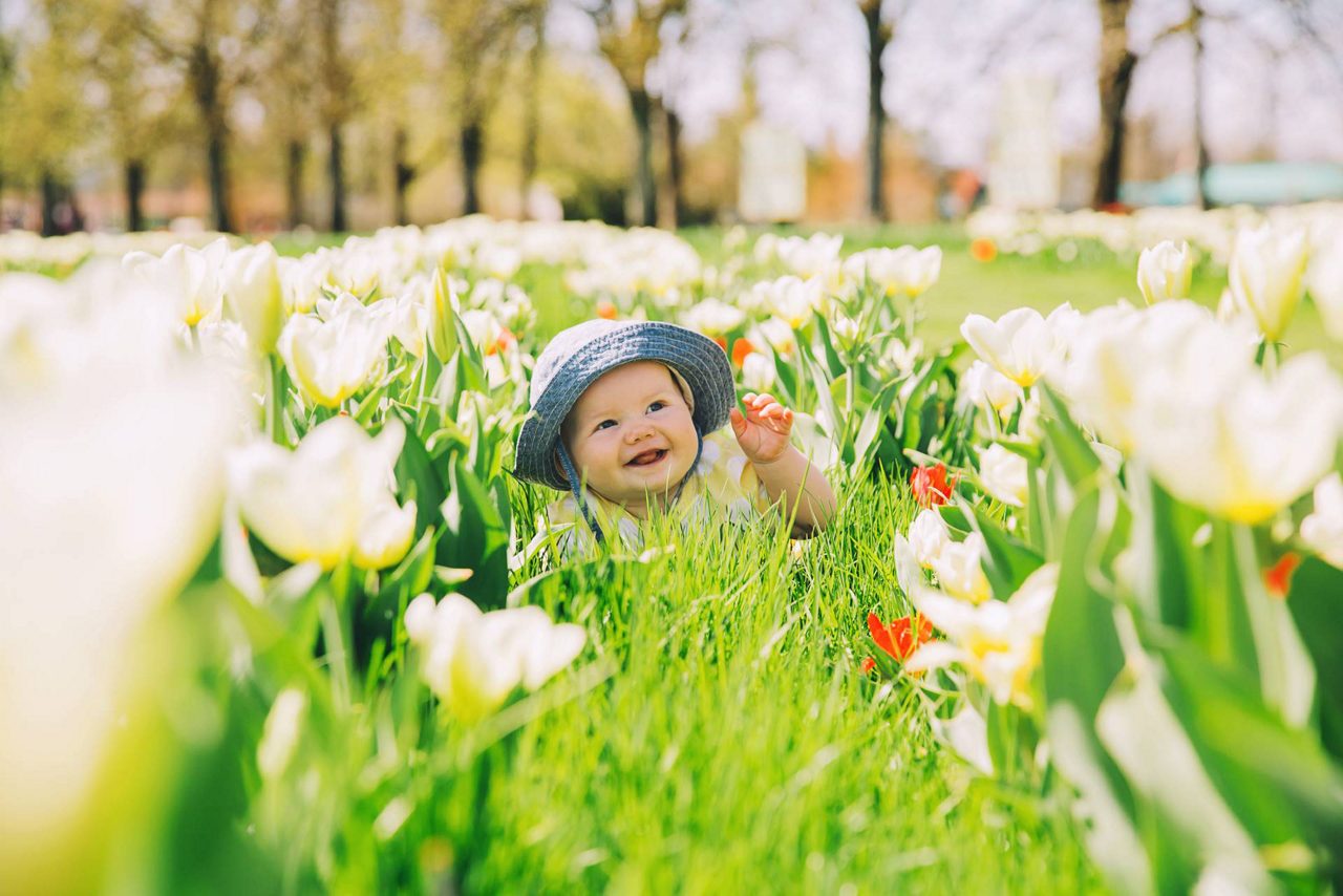 Baby sitzt in einer Blumenwiese