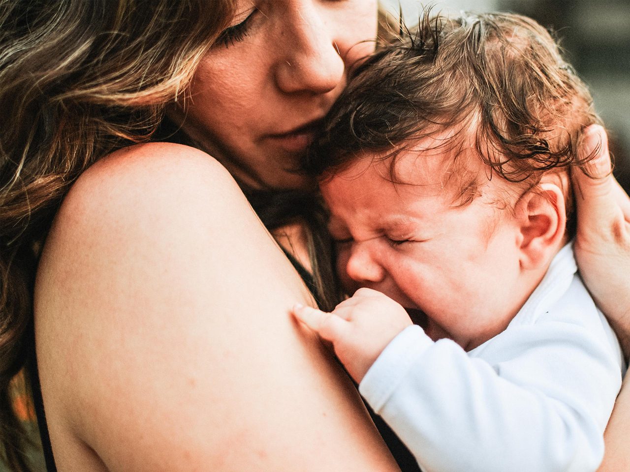 Baby weint in Armen der Mutter