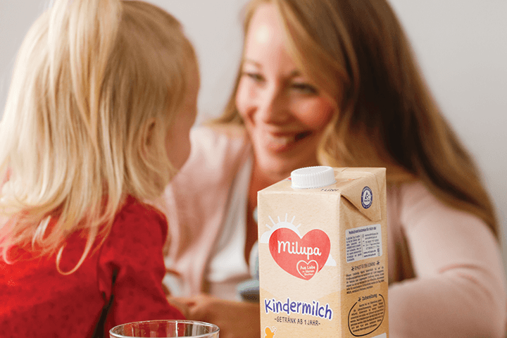Milupa Kindermilch mit Mutter und Kleinkind im Hintergrund