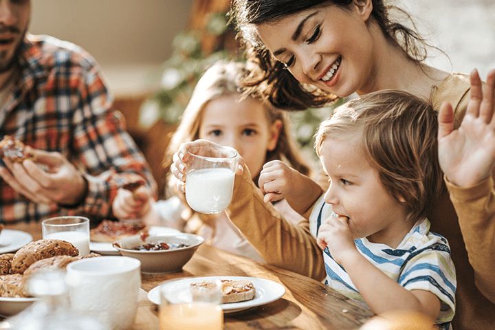 Familie am Frühstückstisch Kleinkind trinkt Kindermilch