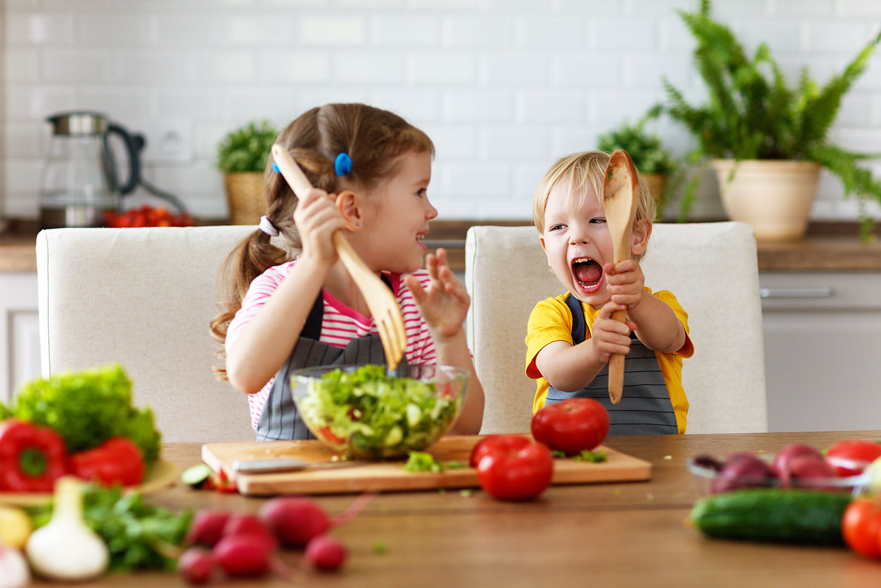 Zwei Kinder spielen mit Salatbesteck