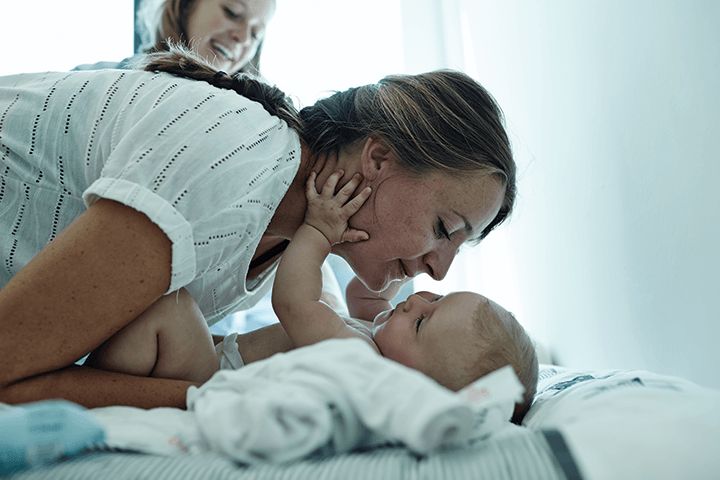 Mutter küsst Baby auf dem Wickeltisch