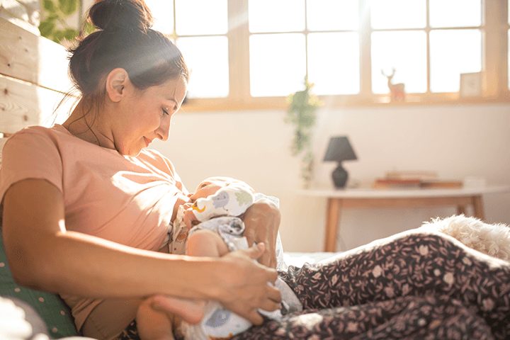Mutter stillt Baby vor sonnigem Fenster