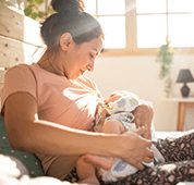 Mutter stillt Baby vor sonnigem Fenster