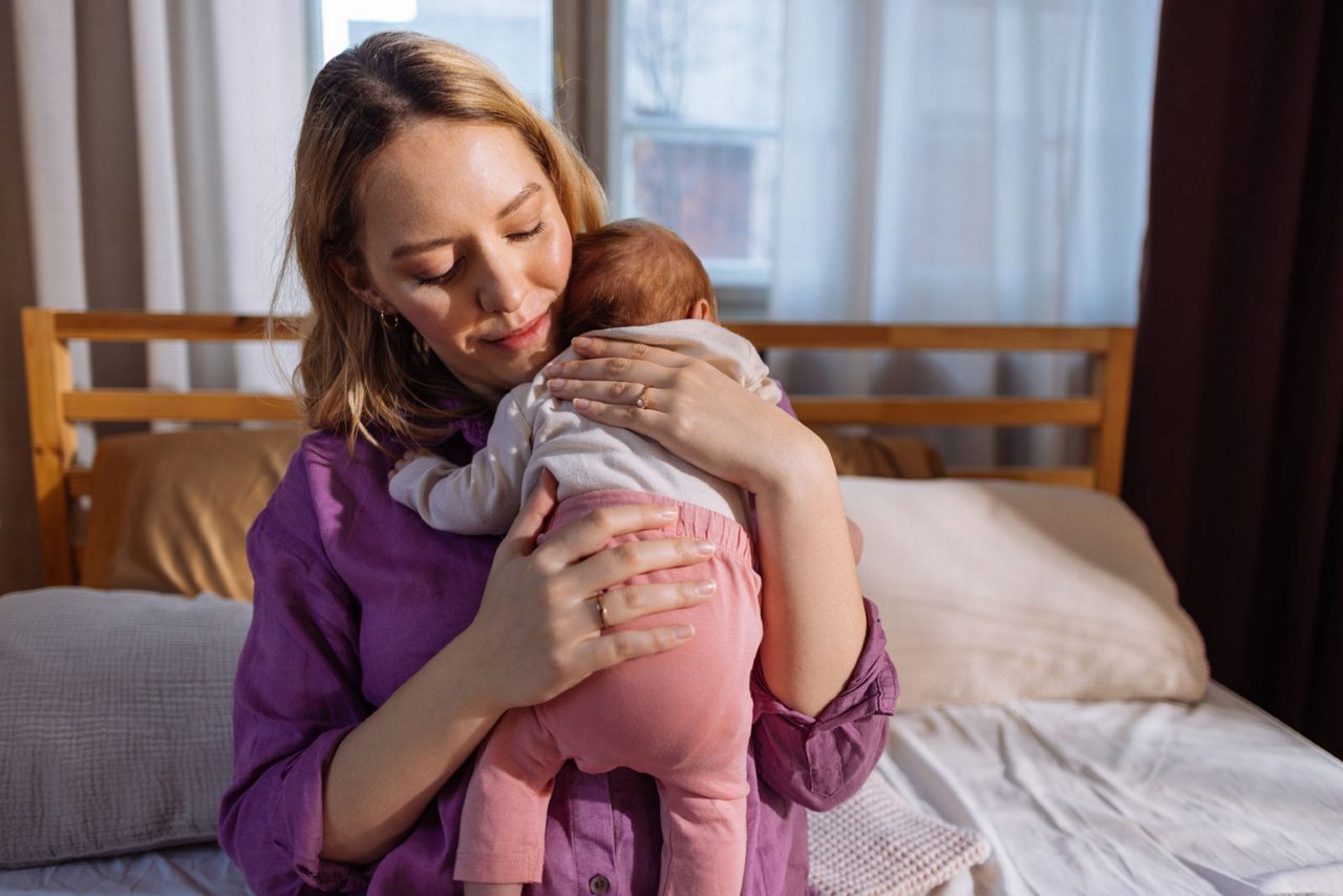 Mama im Wochenbett hält ihr Baby