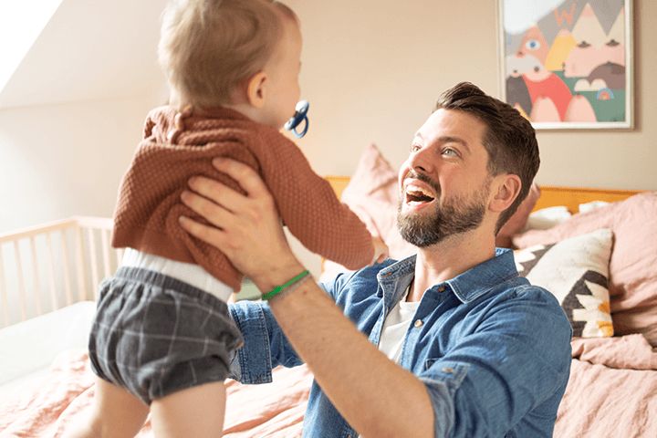 Vater lachend hebt Kleinkind hoch