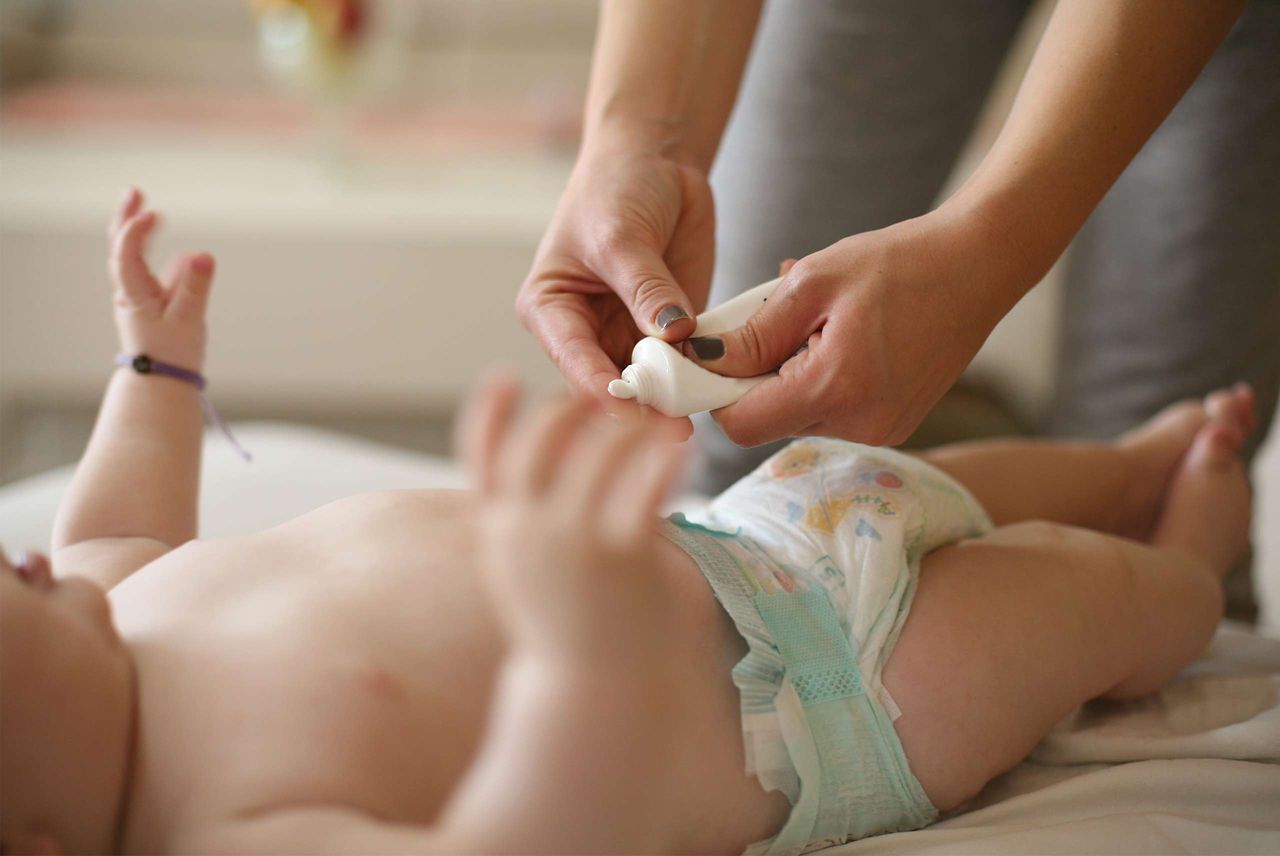 Mutter wickelt Baby und cremt es ein