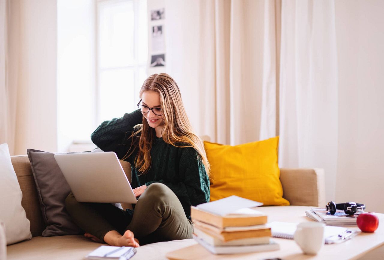 Frau sitzt am Laptop auf der Couch