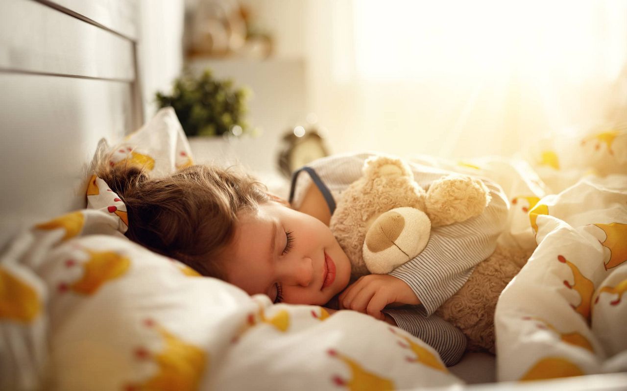 Kleinkind schläft mit Teddybär im Arm