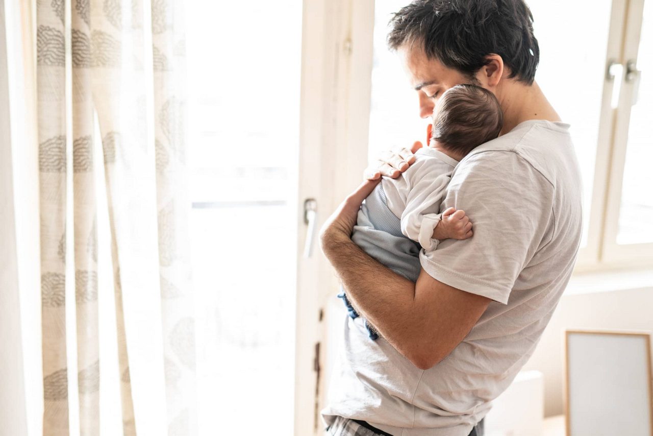 Vater kuschelt mit Baby auf dem Arm 