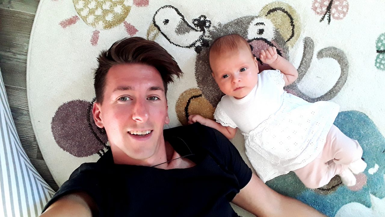 Vater und Baby liegen spielend auf dem Bauch