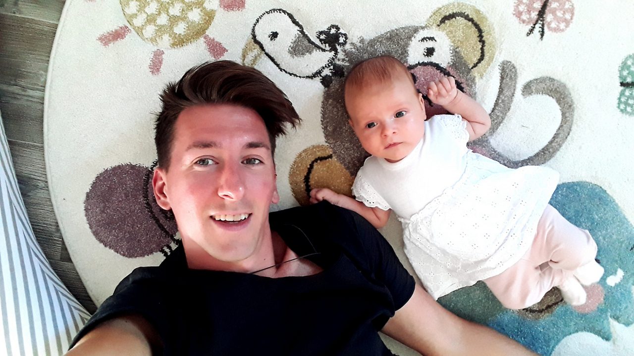 Vater und Baby liegen spielend auf dem Bauch