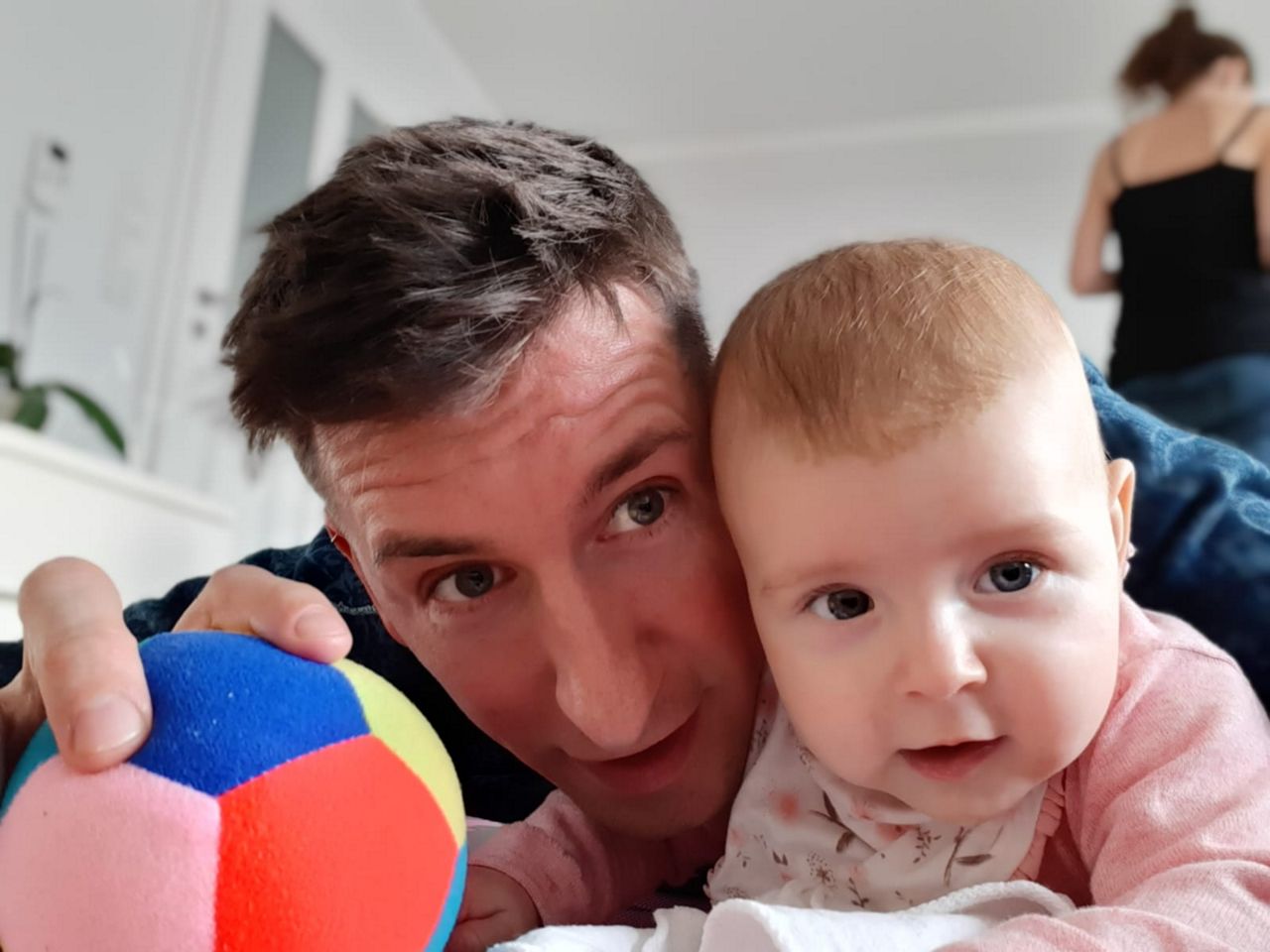 Vater und Baby liegen spielend auf dem Bauch