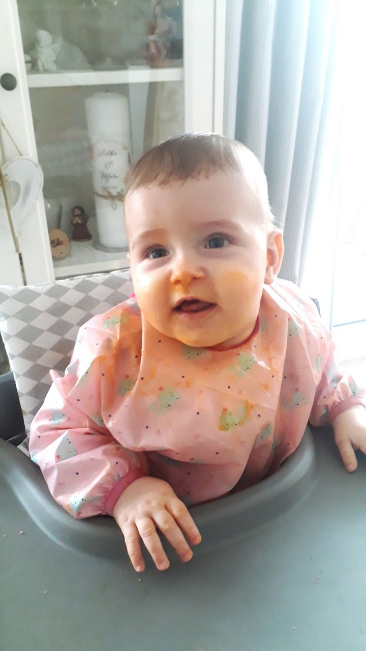 Baby eingesaut mit Brei im Hochstuhl horizontal